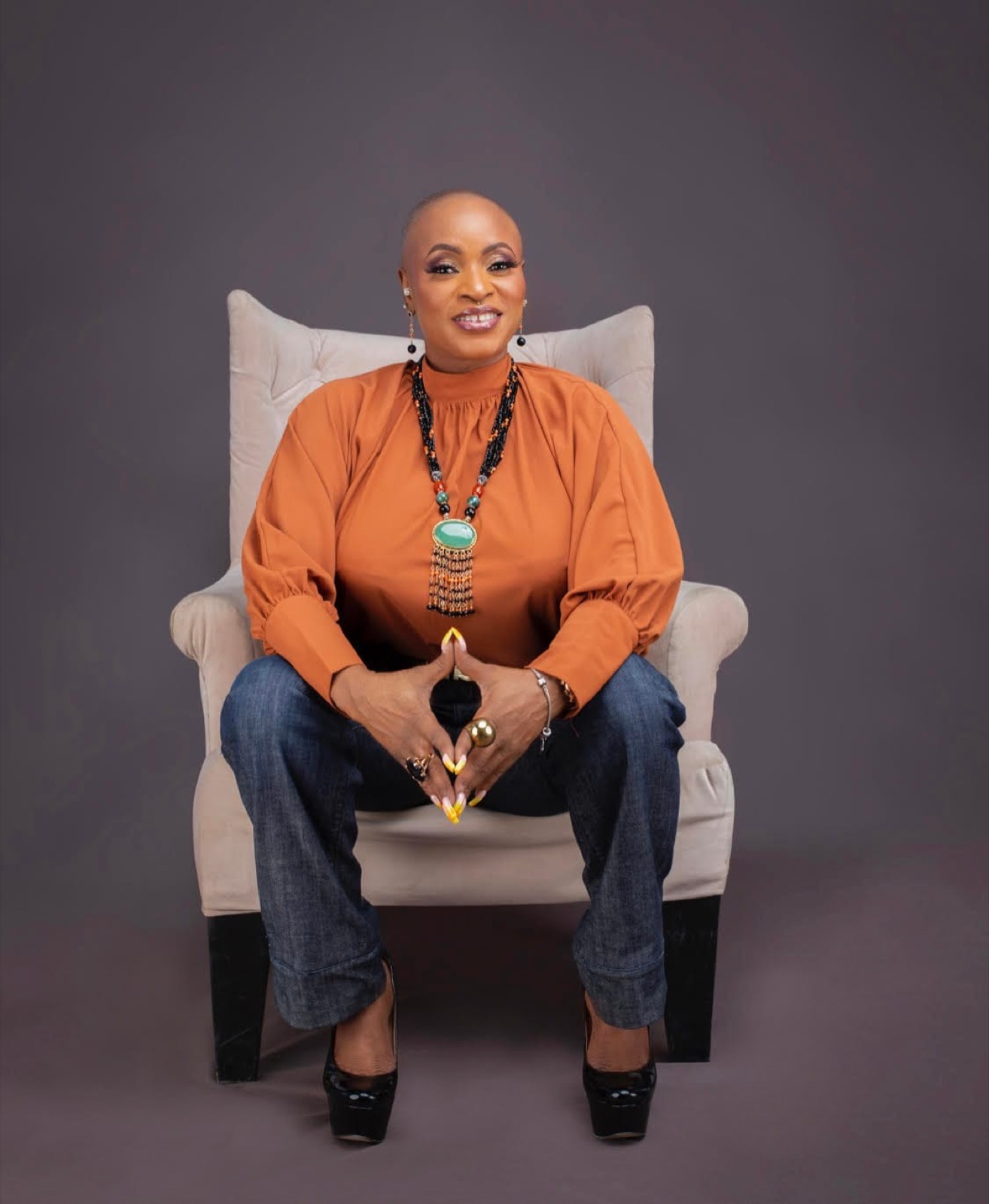 Funke Roberts seated in an armchair in an orange blouse