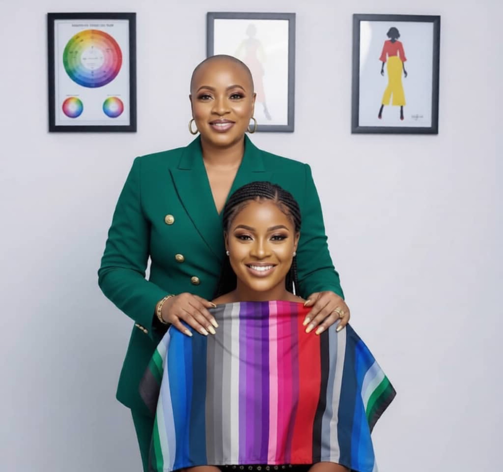 Funke Roberts draping a smiling client in a rainbow color drape