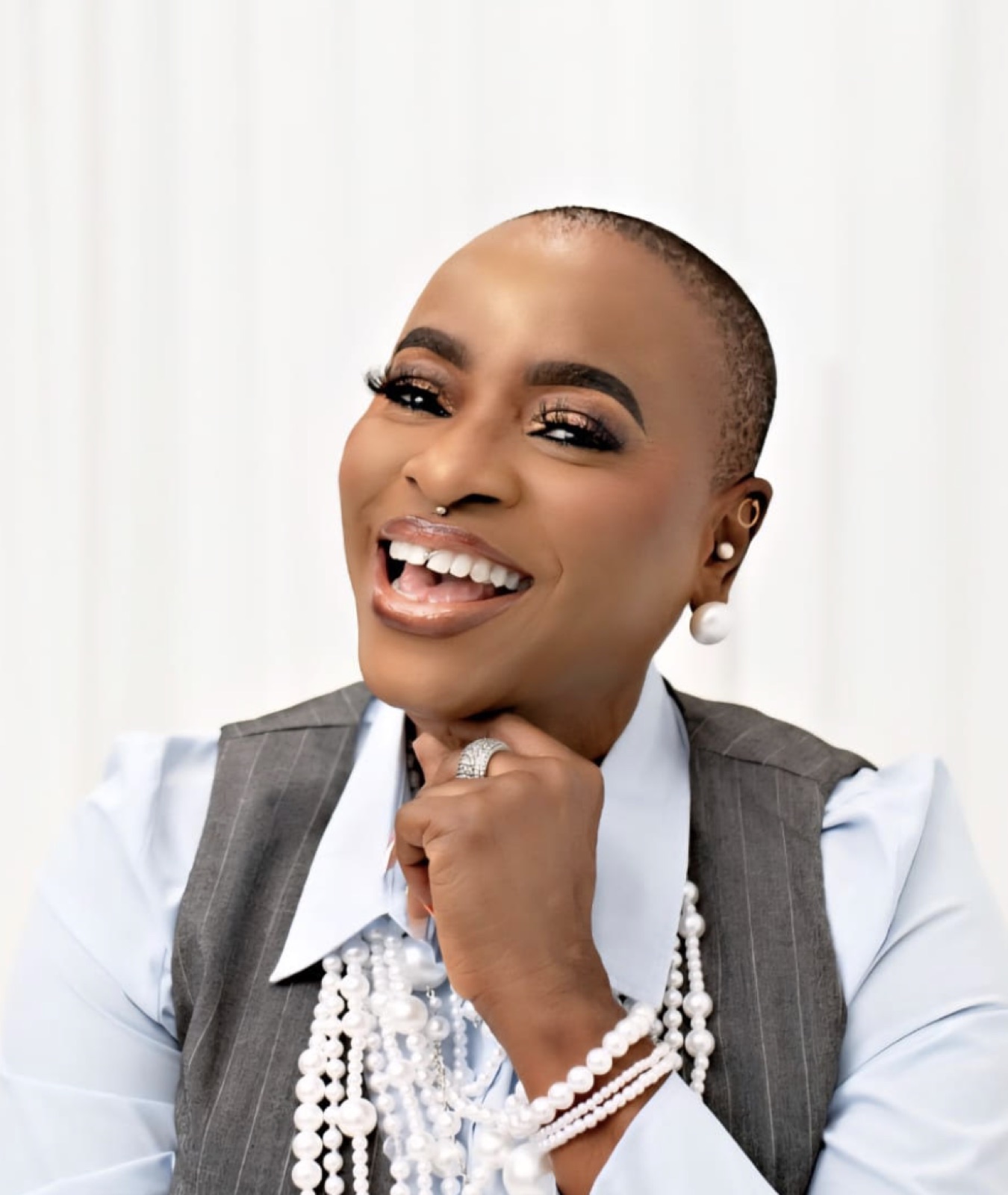 Funke Roberts laughing, pearls and gray vest